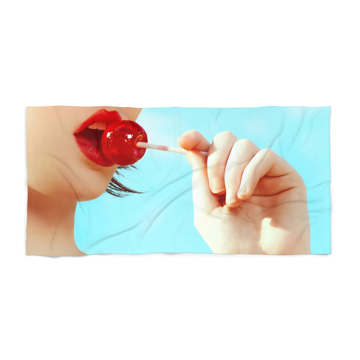 front view of a beach towel of a girl holding a red lollipop up to her red lips
