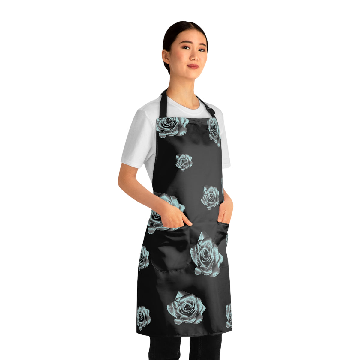 side view of girl wearing a grilling apron with a black and silver rose pattern on it and black straps with both hands in apron pockets