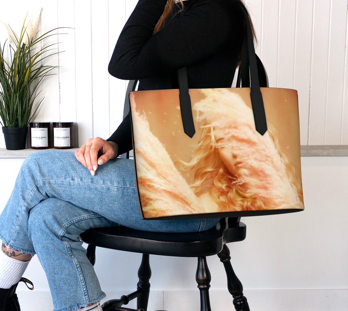 seated woman holding a vegan leather tote bag of a photograph of a young blonde girl holding pink fluffy plumes